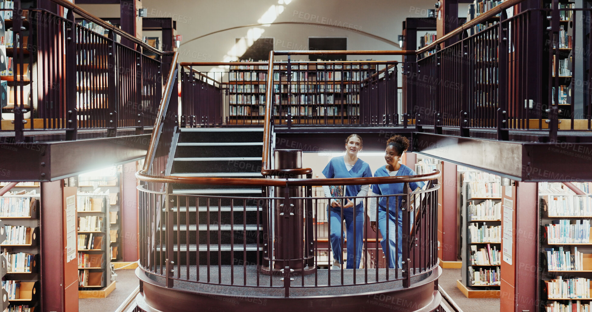 Buy stock photo Nurse, education and women in library, research for anatomy project and university scholarship. Uniform, medical students and people with books, staircase and knowledge for development and discussion