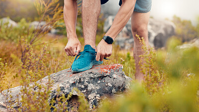 Buy stock photo Man, fitness and tying with sneakers on rock in nature for workout preparation or outdoor exercise. Active, male person or getting ready with hands, laces or shoes for training, hiking or trekking