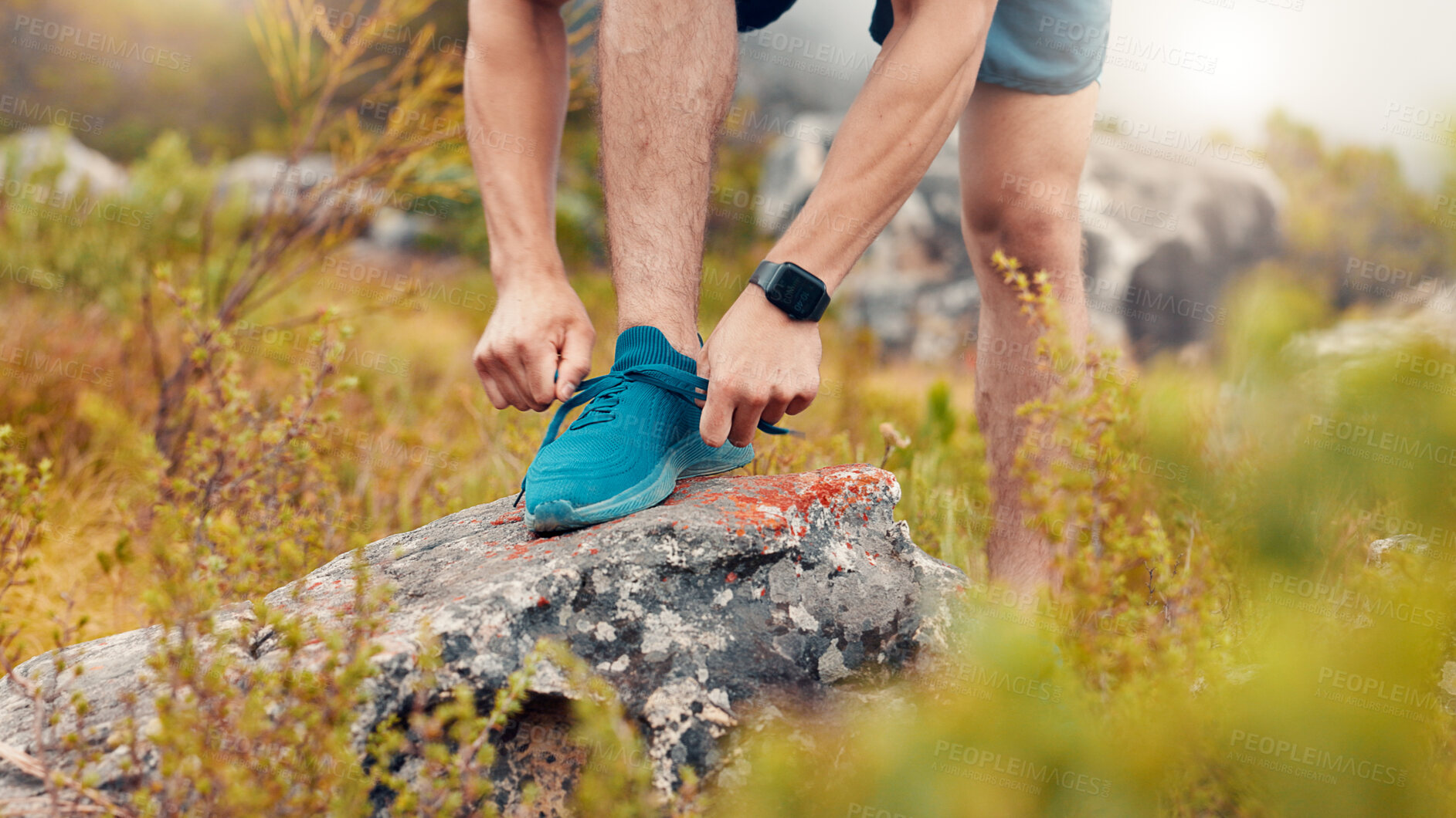 Buy stock photo Man, fitness and tying with sneakers on rock in nature for workout preparation or outdoor exercise. Active, male person or getting ready with hands, laces or shoes for training, hiking or trekking