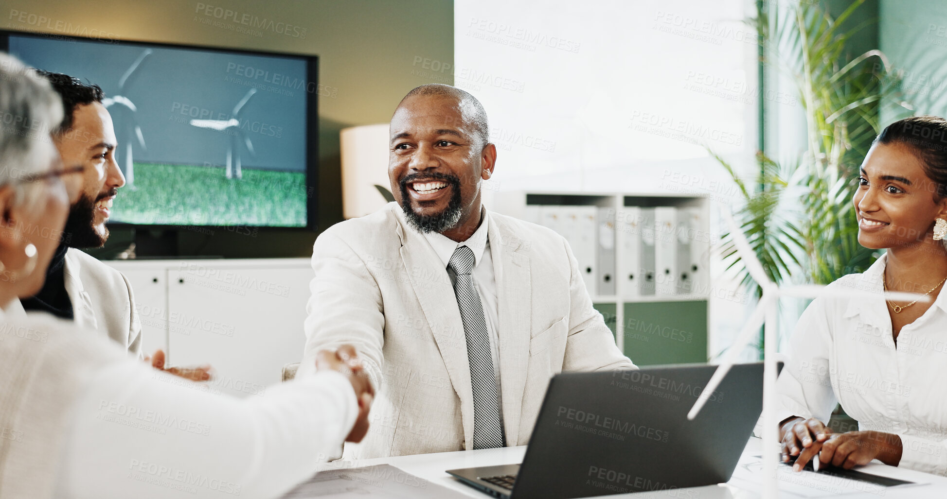 Buy stock photo Laptop, handshake or people with wind turbine in office, clean energy deal or eco friendly partnership. Smile, teamwork or group with sustainability agreement for green policy, shaking hands or pc