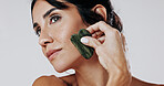 Woman, facial and skincare with gua sha in studio for anti aging massage on a white background. Female person, model or thinking with jade or stone for beauty treatment, cosmetology or dermatology