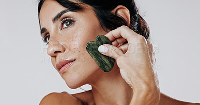 Buy stock photo Woman, facial and skincare with gua sha in studio for anti aging massage on a white background. Female person, model or thinking with jade or stone for beauty treatment, cosmetology or dermatology