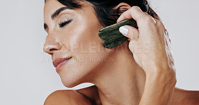 Buy stock photo Woman, facial and skincare with gua sha for anti aging massage on a white studio background. Female person, model or relaxing with jade or stone for beauty treatment, cosmetology or dermatology