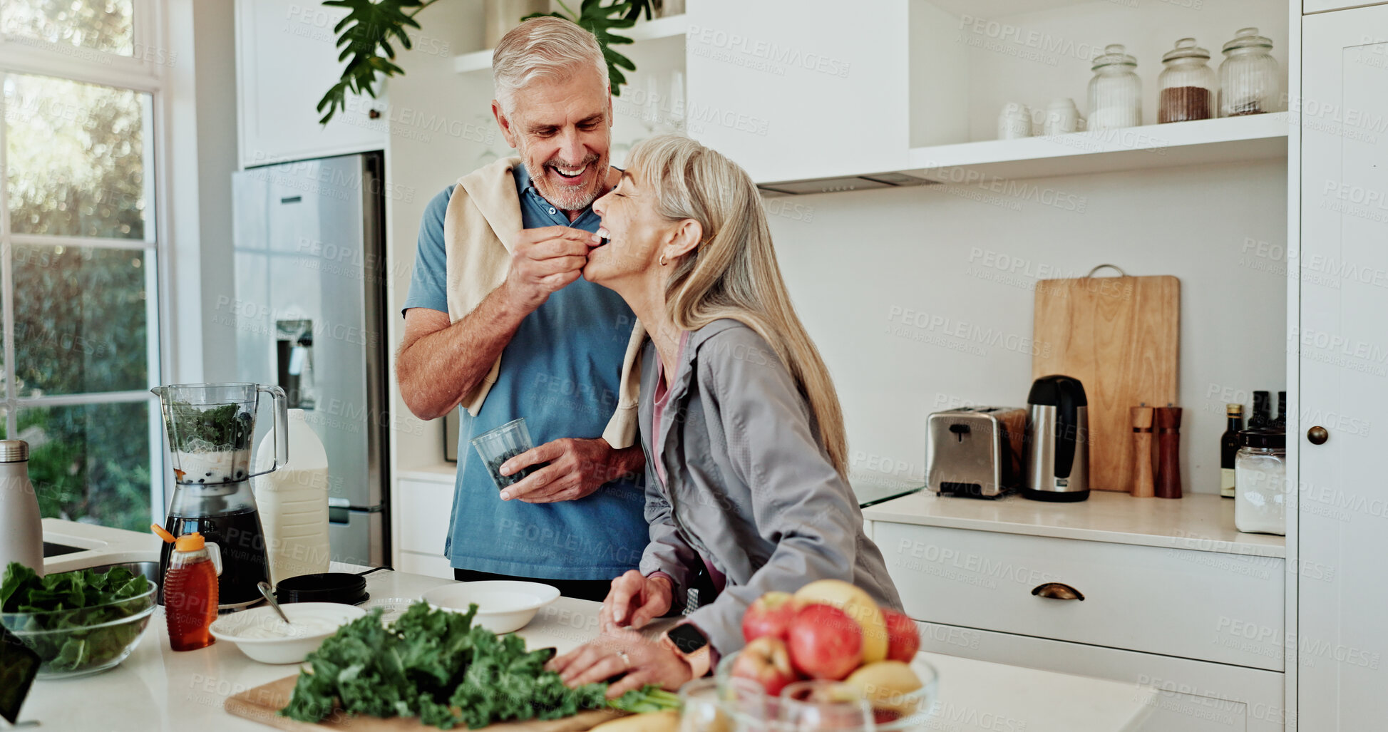 Buy stock photo Feed, fruit and old couple in kitchen with smoothie recipe, healthy diet and wellness for retirement. Married senior people, taste blueberry and bonding in home with breakfast, nutrition and support.