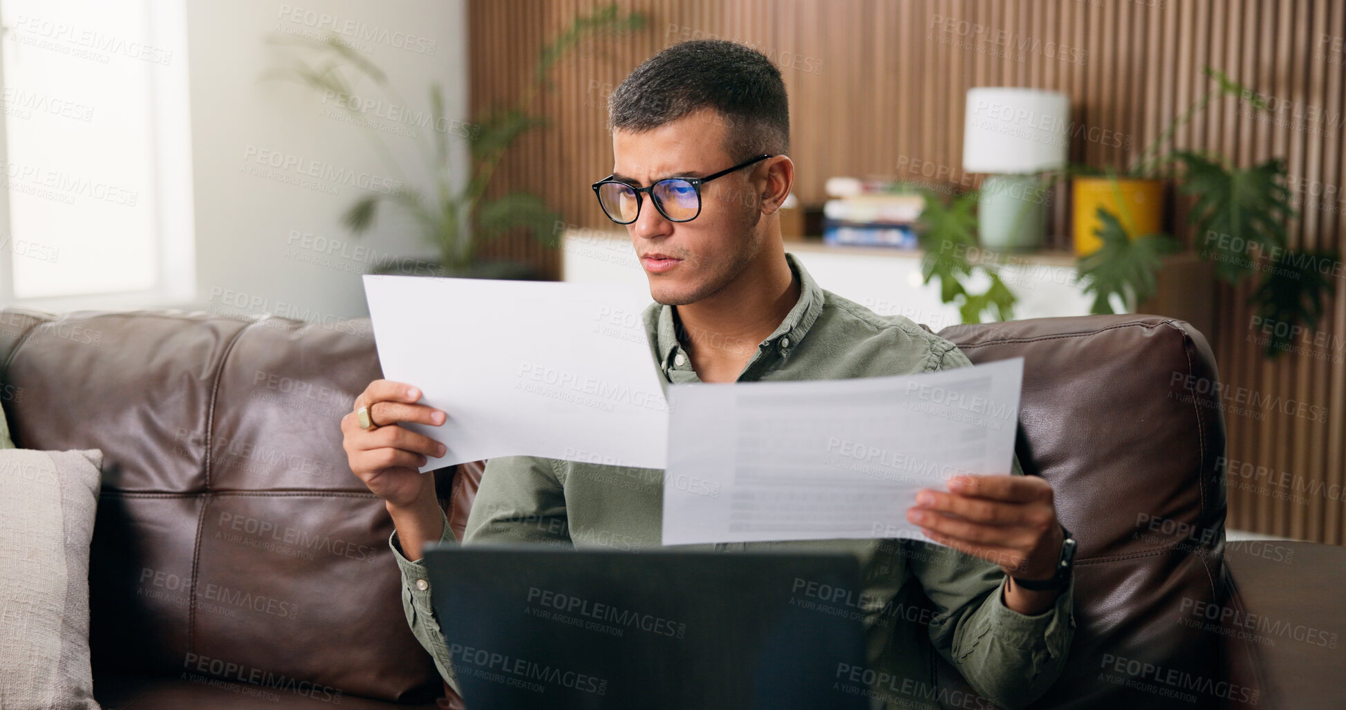 Buy stock photo Man, reading and documents with laptop in home for finanial planning, audit or investment on sofa. Male person, checking and paperwork with insurance on computer for budget, finance bills or expenses