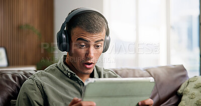 Buy stock photo Shock, tablet and man on sofa with headphones for online videos, subscription and watching movies. Home, reaction and person on digital tech for internet, website and streaming drama show on weekend