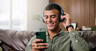 Buy stock photo Man, phone and happy with headphones on couch for streaming, smile and sound in living room at house. Person, smartphone and listen to music with subscription, mobile app or audio on sofa in home