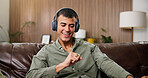 Man, smile and dance with headphones on sofa for streaming, song and sound in living room at house. Person, smartphone and listen to music with subscription, audio or happy for rhythm at apartment