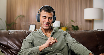 Buy stock photo Man, smile and dance with headphones on sofa for streaming, song and sound in living room at house. Person, smartphone and listen to music with subscription, audio or happy for rhythm at apartment