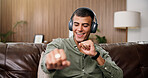 Man, happy and dance with headphones on sofa for streaming, song and sound in living room at house. Person, smartphone and listen to music with subscription, audio or smile for rhythm at apartment