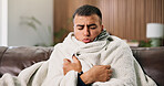 Man, sick and rest with blanket on sofa with cold symptoms, virus and fatigue in living room at house. Person, flu or illness on couch with comfort, break and recovery for healing at apartment