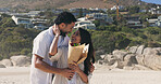 Smile, couple and hug with bouquet at beach for romantic date, celebration and bonding together. Happy, people and embrace with flowers for romance, anniversary getaway and surprise gift at seaside
