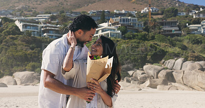 Buy stock photo Smile, couple and hug with bouquet at beach for romantic date, celebration and bonding together. Happy, people and embrace with flowers for romance, anniversary getaway and surprise gift at seaside