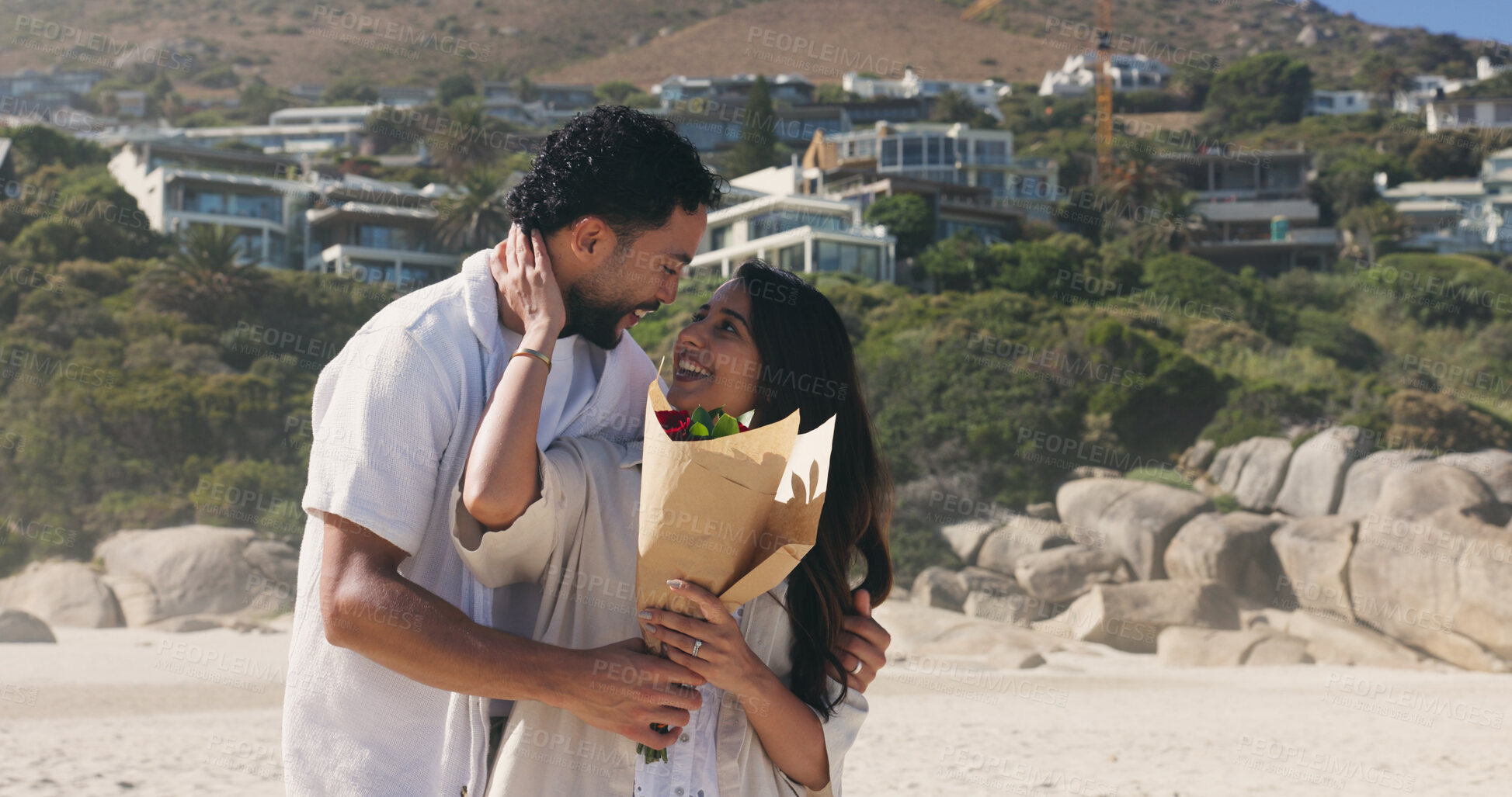 Buy stock photo Smile, couple and hug with bouquet at beach for romantic date, celebration and bonding together. Happy, people and embrace with flowers for romance, anniversary getaway and surprise gift at seaside