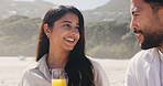 Smile, couple and relax with love at beach for romantic date, celebration and bonding together. Happy, people and picnic with orange juice for romance, anniversary getaway and holiday trip at seaside