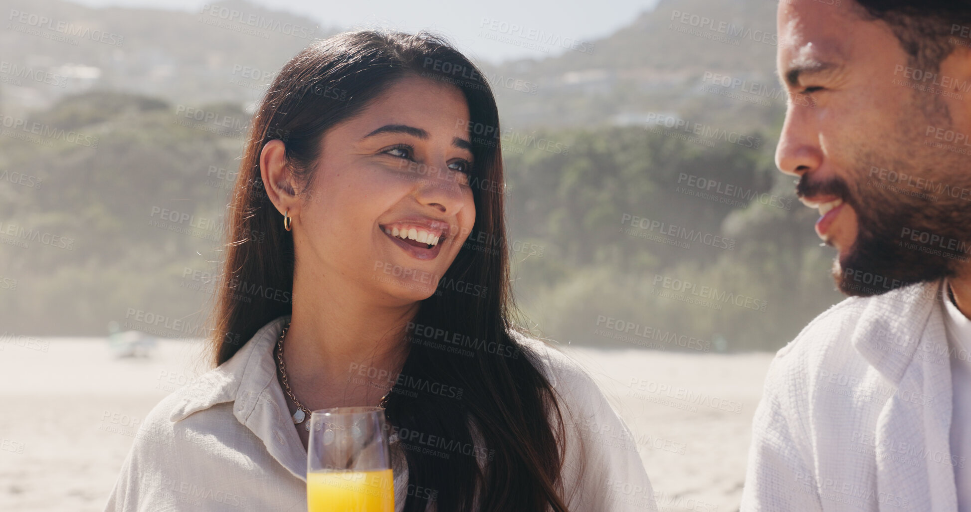 Buy stock photo Smile, couple and relax with love at beach for romantic date, celebration and bonding together. Happy, people and picnic with orange juice for romance, anniversary getaway and holiday trip at seaside