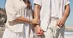 Holding hands, couple and care on walk at beach with loyalty, holiday and love with bonding in summer. People, partner and relationship with marriage, honeymoon and connection on seaside vacation