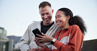 Buy stock photo Happy couple, fitness and phone with break in city for meme, notification or share post on bridge. People, runner and smartphone with app, smile or interracial relationship for exercise in urban town