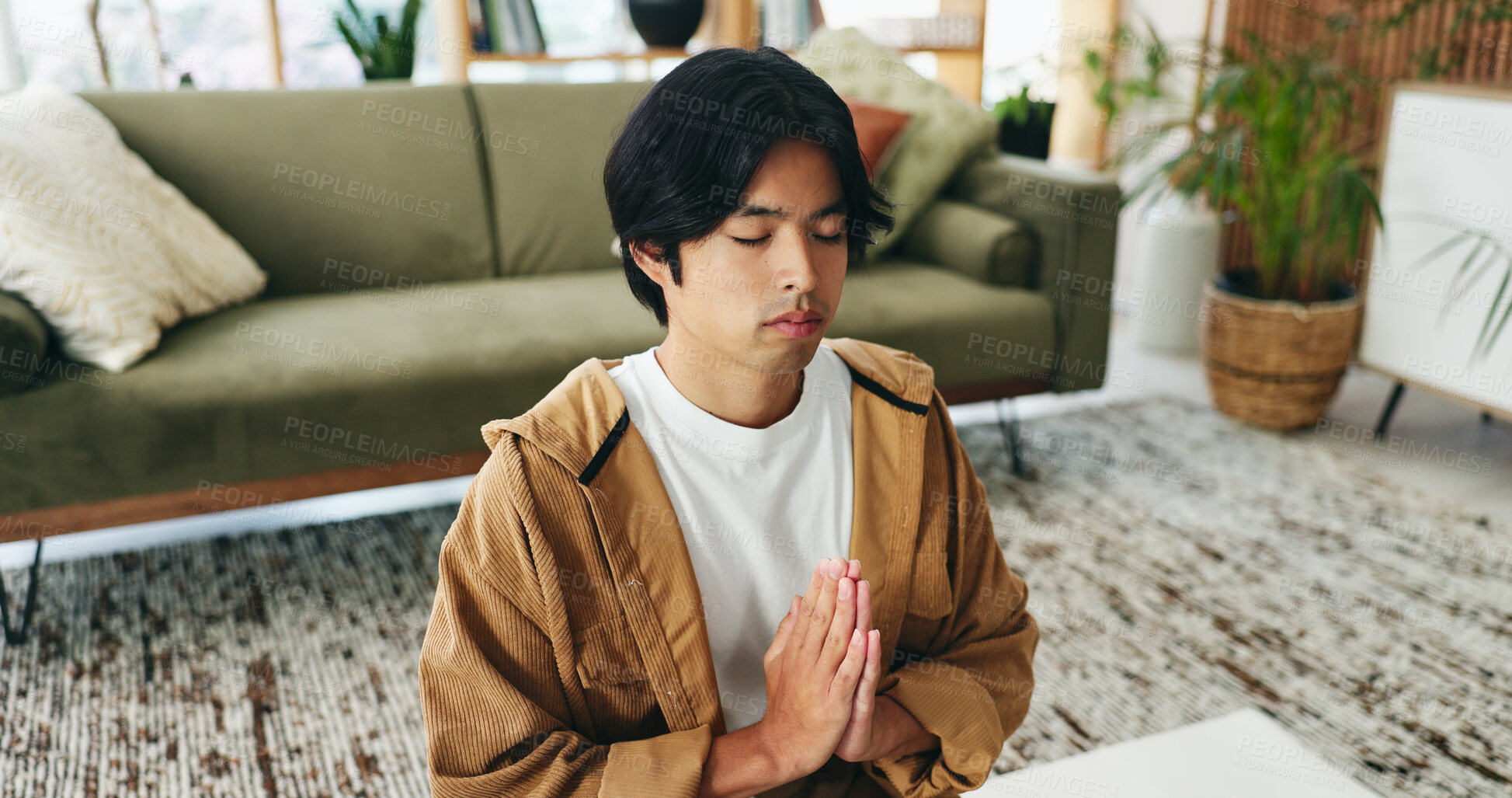 Buy stock photo Zen, man and meditation with prayer in lounge, mindfulness and calm with spiritual awareness in home. Person, wellness and self care for mental health on break, relax or healing with yoga and balance