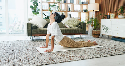Buy stock photo Headphones, stretching and yoga with man on floor in home living room for exercise or wellness routine. Fitness, health and music with Asian person in cobra pose for balance or holistic activity