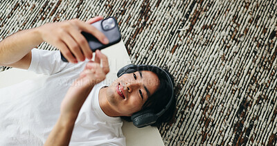Buy stock photo Yoga mat, music and Asian man with smartphone in home for sound, pilates playlist and top view. Mobile, headphones and happy person on floor for fitness podcast, wellness audio and streaming service