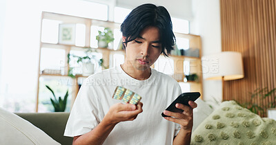 Buy stock photo Phone, pills and man in home for research, healthcare information or reading label for dose. Mobile, drugs and Asian person in house for medical prescription, medicine benefits or side effects