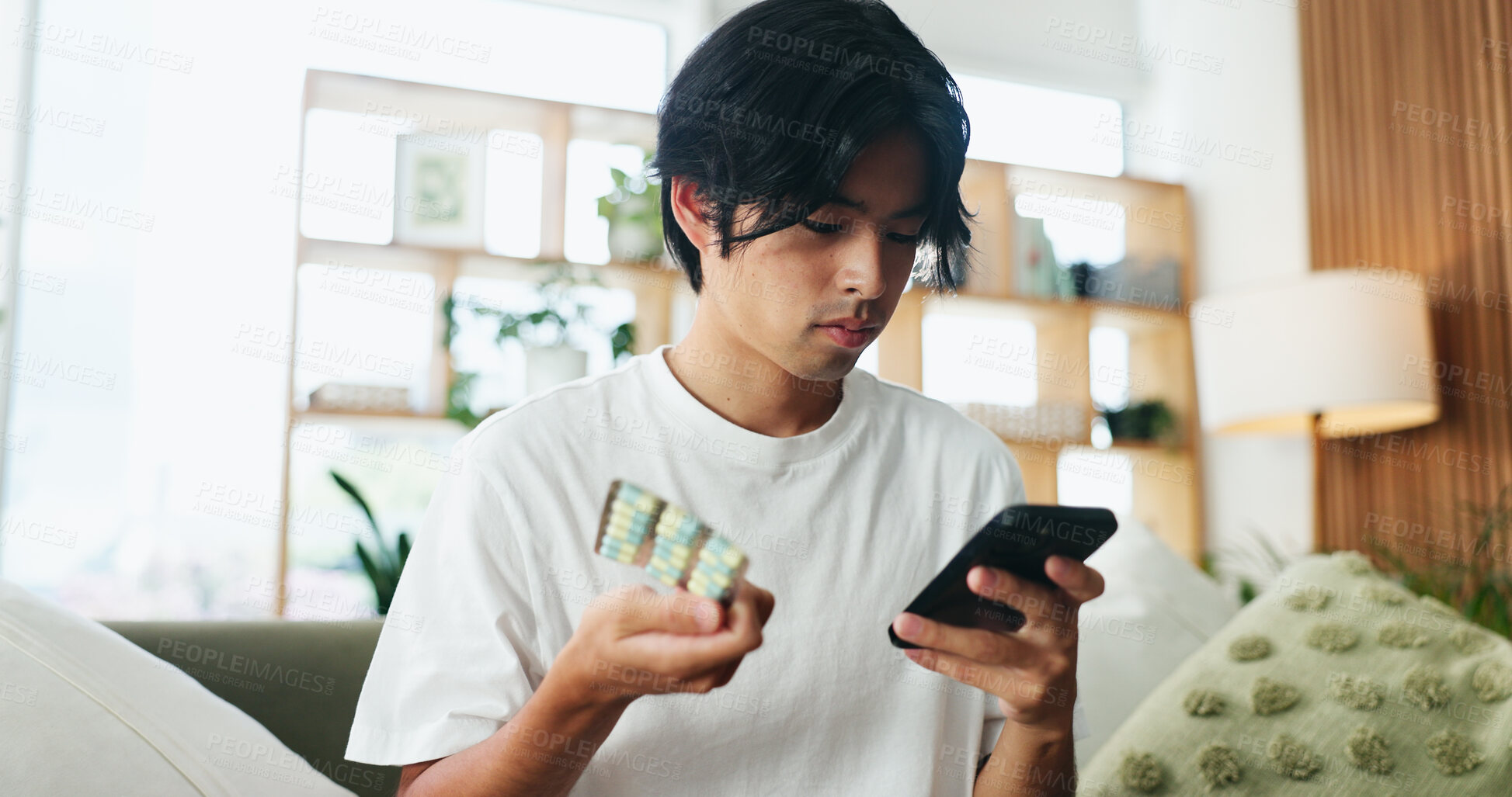 Buy stock photo Man, phone and medication in home with search on web for side effects, ingredients or allergies on sofa. Person, smartphone and check pills on mobile app, supplements and drugs for wellness in house