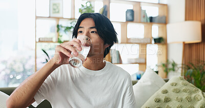 Buy stock photo Man, drinking and home with water on sofa for hydration, thirst or natural vitamin detox. Male person, relax and beverage with mineral liquid on living room couch for sustainability or diet in house