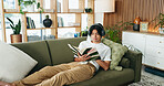 Relax, headphones or man reading book on couch, emotional wellness guide or streaming author podcast. Home, Asian person or audio tech for ambient playlist, subscription service or literature for zen