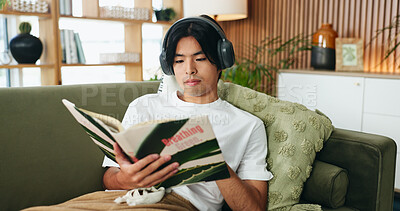 Buy stock photo Relax, headphones or man reading book on sofa, emotional wellness guide or streaming author podcast. Home, Asian person or audio tech for ambient playlist, subscription service or literature for zen