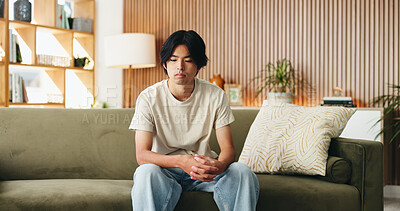 Buy stock photo Thinking, anxiety and man on sofa in home with regret for decision or choice with mental health. Upset, uncertain and Asian male person with reflection for mistake, failure or bad news in living room