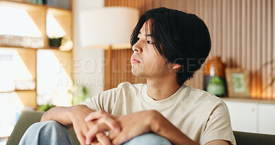 Buy stock photo Thinking, sad and man on sofa in house with regret for decision or choice with mental health. Anxiety, uncertain and Asian male person with reflection for mistake, failure or bad news in living room.