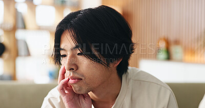 Buy stock photo Uncertain, sad and man on sofa in home with regret for decision or choice with mental health. Anxiety, thinking and Asian male person with reflection for mistake, failure or bad news in living room.