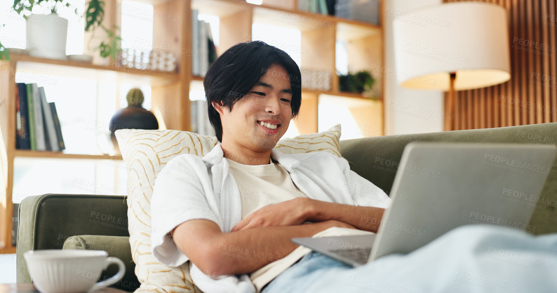 Buy stock photo Laptop, smile and study with Asian man on sofa in home living room for distance learning. Computer, online education and streaming with happy university student in apartment for development or growth