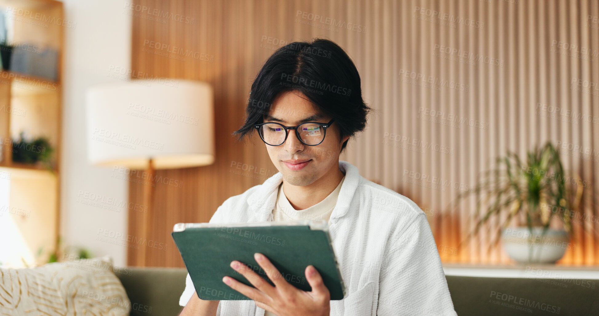 Buy stock photo Education, glasses and tablet with Asian man on sofa in home living room for distance learning. App, eyewear and online study with university student in apartment for development or streaming