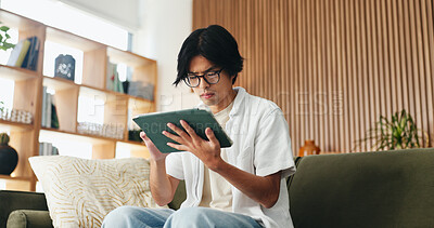 Buy stock photo Glasses, study and tablet with Asian man on sofa in home living room for distance learning. App, eyewear and online education with university student in apartment for development or streaming