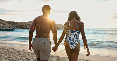 Buy stock photo Couple, holding hands and bonding on beach holiday, sunrise and together on summer adventure or date. Back, people and affection for partner at sea, flare and outdoor for anniversary and romance