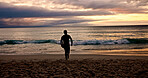 Surfboard, sunset and walking with man on beach for holiday activity, sports or weekend getaway. Hobby, vacation and waves with surfer outdoor on sand at coast for fitness or training in summer