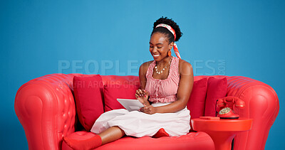Buy stock photo Smile, studio and tablet with black woman on sofa for social media browsing, post or search. App, relax and scrolling with happy African person on blue background for digital connection or download