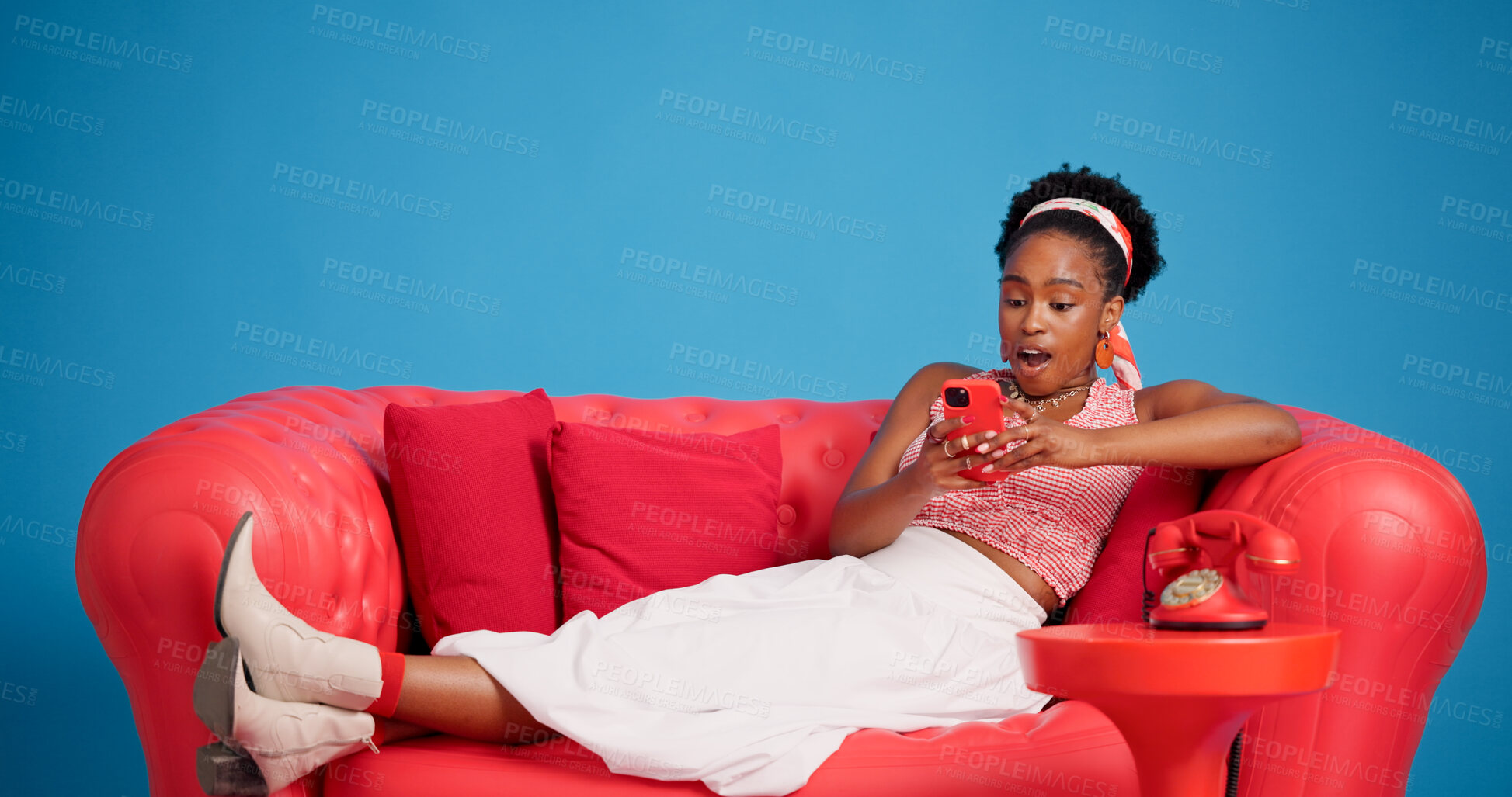 Buy stock photo Phone, studio and wow with black woman on sofa for social media browsing, post or search. App, reaction and surprise with African person in shock on blue background for text message or typing