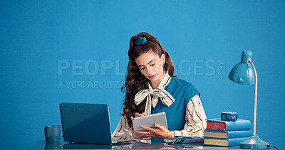 Buy stock photo Design, studio and tablet with woman at desk for creative development, planning or retro research. App, laptop and scrolling with vintage designer on blue background for artistic career, job or work