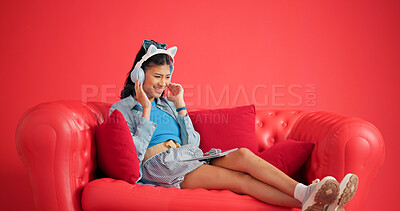 Buy stock photo Woman, couch and headphones in studio with tablet, browsing website and listening to music playlist. Happy, female person and audio tech on sofa with online radio, streaming service and digital app.