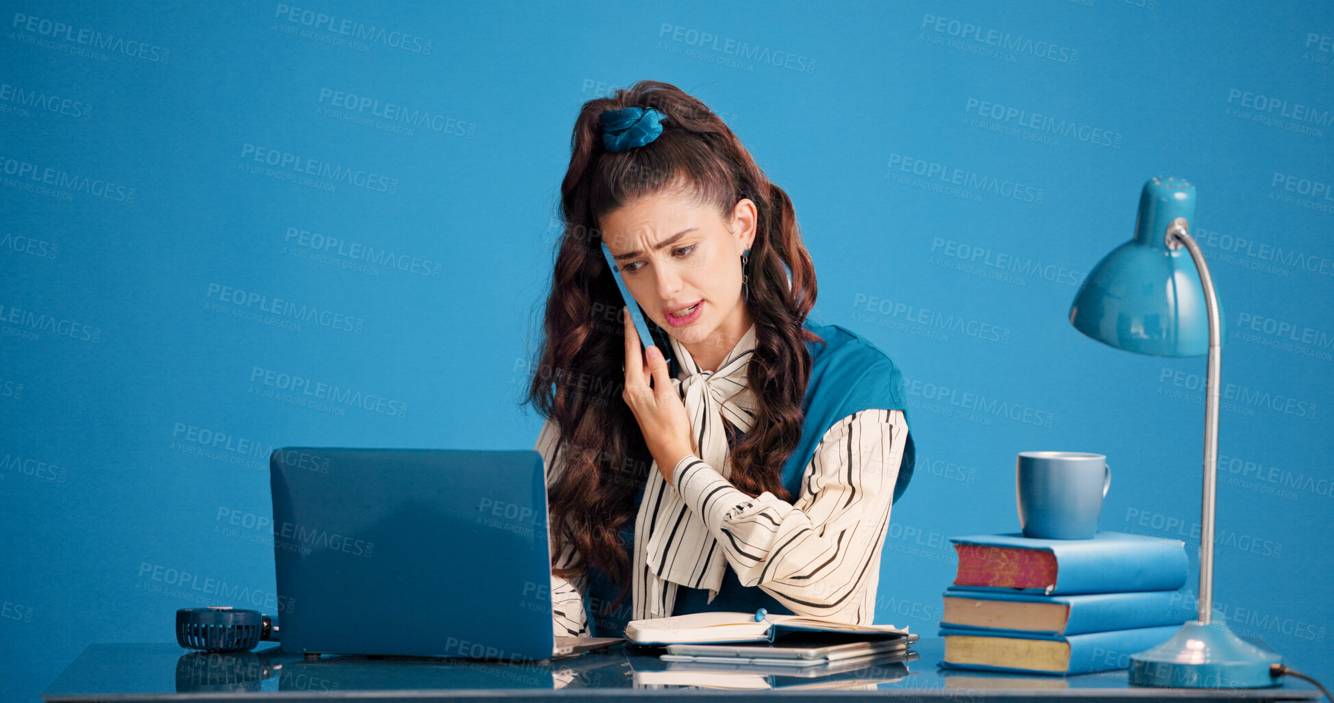 Buy stock photo Laptop, phone call and stress with woman in studio for business discussion, feedback or negotiation. Computer, conversation and problem solving with employee person on blue background for contact