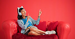Woman, couch and headphones in studio with dance, tablet and listening to popular music playlist. Happy, person rhythm and audio tech with sofa, online radio and streaming song on red background.