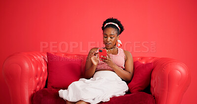 Buy stock photo Phone, relax and black woman on sofa in studio with texting, chatting or social media on mobile app. Calm, technology and African female person with cellphone for contact online by red background.