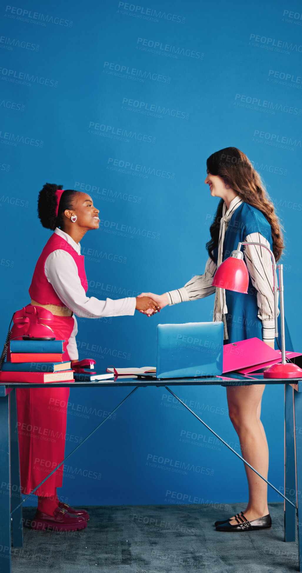 Buy stock photo Deal, handshake and partnership with women in studio together for collaboration or retro business. Meeting, thank you and welcome with employee people shaking hands on blue background for agreement