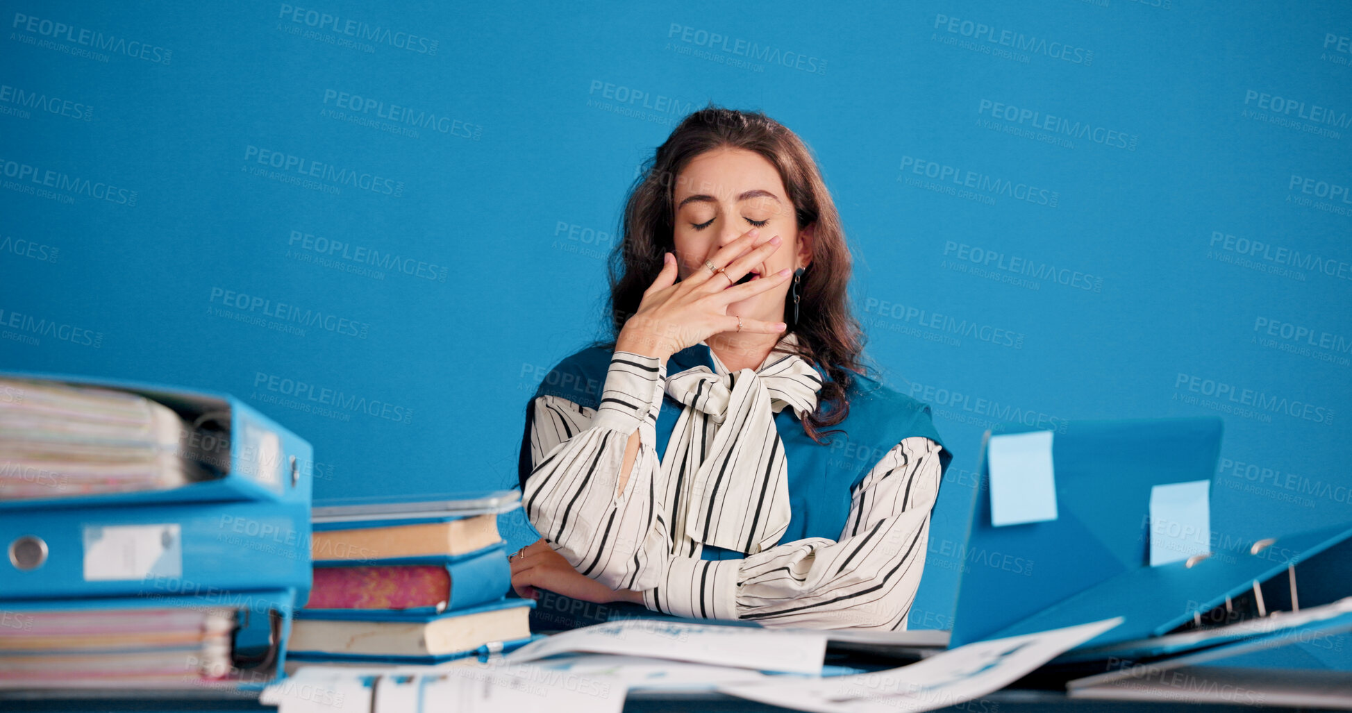 Buy stock photo Laptop, files and businesswoman with yawn in studio for filing workload, low energy or fatigue. Tech, folders and tired admin assistant on blue background for data entry burnout, overworked and space