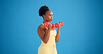Black woman, dumbbells and exercise in studio with weightlifting for strength training on blue background. African person, bodybuilder and mockup space for strong muscle, fitness or workout with gear