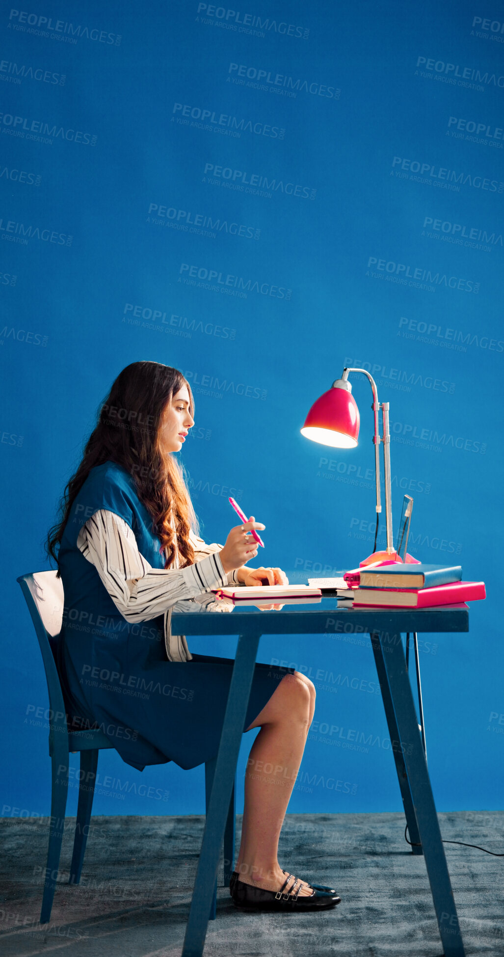 Buy stock photo Laptop, notebook and space with designer woman at desk in studio for agenda, calendar or schedule. Computer, journal and thinking with employee person on blue background for small business planning