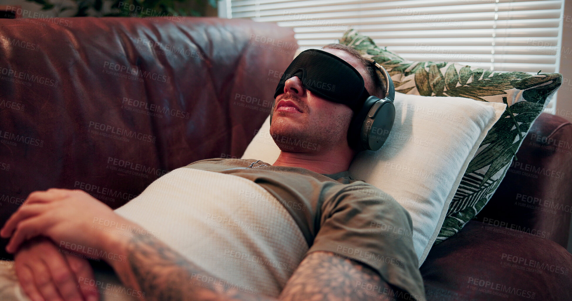 Buy stock photo Headphones, psychology and man with blindfold on sofa, sensory deprivation and anxiety counseling. Relaxation therapy, calm and person with mindfulness training for ptsd, therapeutic audio and tech